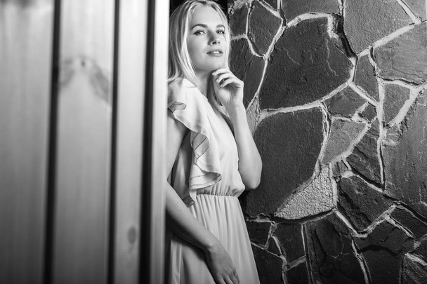Young blond beauty woman against house interior. Black-white portrait. - Photo, Image