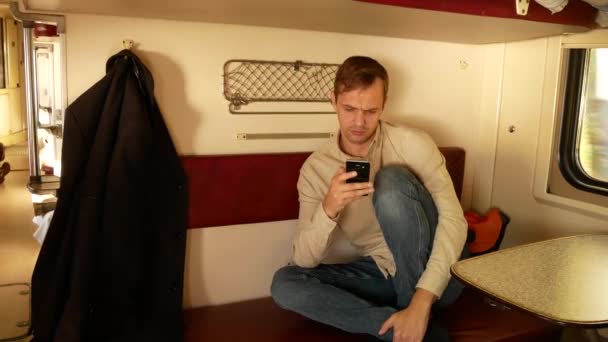 Egy személy használ egy smartphone egy rekeszbe a személyszállító vonat. 4k - Felvétel, videó