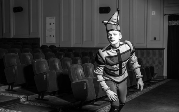 Actor dressed jester's costume in interior of old theater. Black-white portrait. - Photo, Image