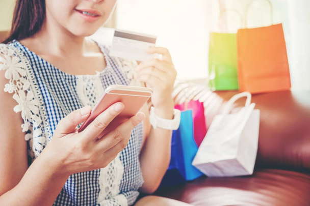 Woman shopping online using smartphone with credit card enjoying - Foto, Imagen