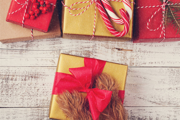 Pelirroja piernas peludas perro sosteniendo caja de regalo de Navidad sobre fondo de madera blanca. vista superior
 - Foto, Imagen