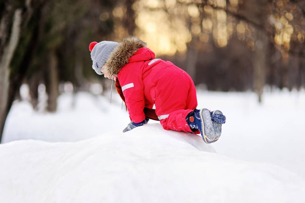 Little boy in red winter clothes having fun with fresh snow - Foto, Imagem