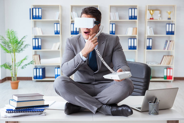 Businessman in virtual reality VR glasses meditating at desk top - Фото, изображение