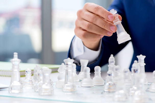 Giovane uomo d'affari che gioca a scacchi di vetro in ufficio - Foto, immagini