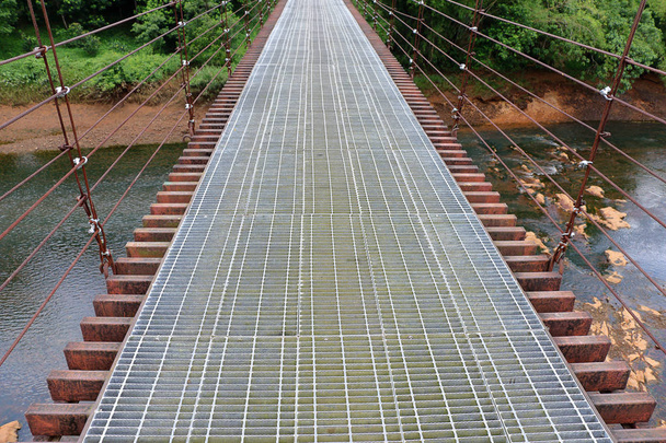 Подвесный мост ведет к джунглям через реку.
. - Фото, изображение
