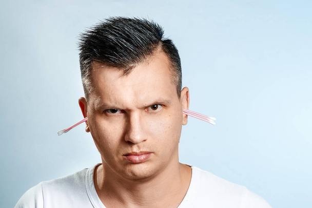 The man with the help of a hygienic cotton swab is reading his ear. The concept of body hygiene. - Fotoğraf, Görsel