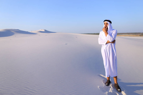 Hombre árabe majestuoso mira duro en la distancia y reflexiona, de pie
 - Foto, Imagen