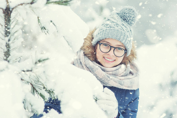 Schoonheid Winter meisje waait sneeuw in ijzig winter park of buiten. Meisje en winter koud weer - Foto, afbeelding