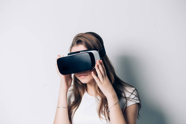 Young woman using a virtual reality headset on a white background - Foto, afbeelding