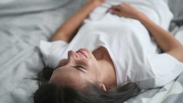 Nice young woman lying in bed - Кадри, відео