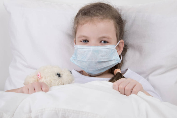 child in white bed, on his face is wearing a medical mask, against the flu - Foto, Bild