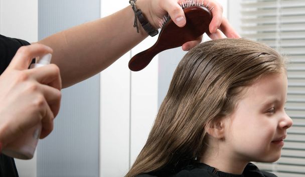 young girl doing a hairdress, wetting her hair, she smiles - Foto, afbeelding