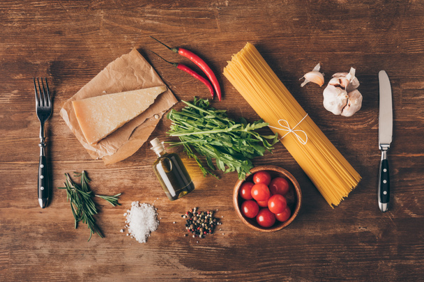 木製のテーブルの行のパスタ、新鮮な食材、パルメザン チーズ、フォークとナイフのトップ ビュー - 写真・画像