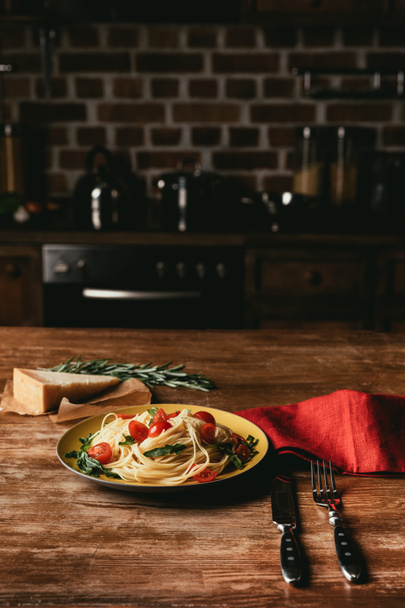 pasta con pomodori e rucola in piatto sul tavolo con parmigiano e rosmarino
 - Foto, immagini