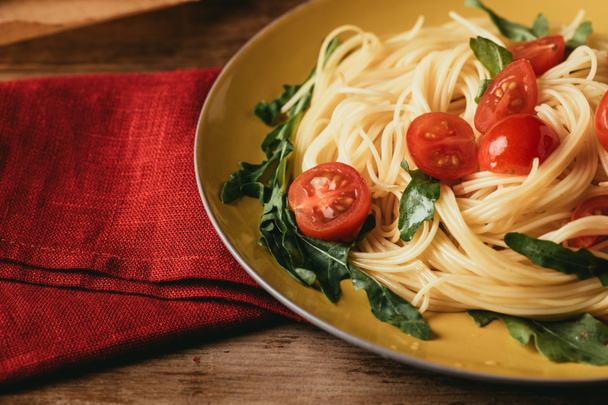Close up van traditionele Italiaanse pasta met tomaten en rucola in plaat - Foto, afbeelding