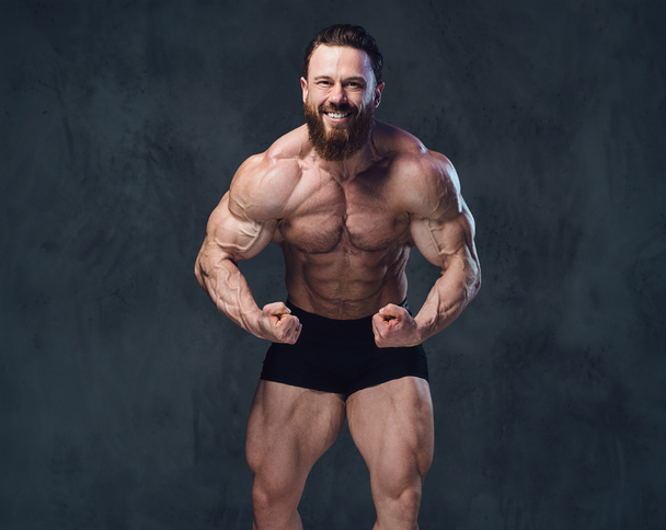Portrait of bearded shirtless bodybuilder over grey background. - Photo, Image
