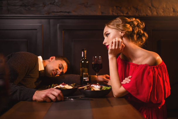 Drunk man sleeping at table against woman  - Photo, Image