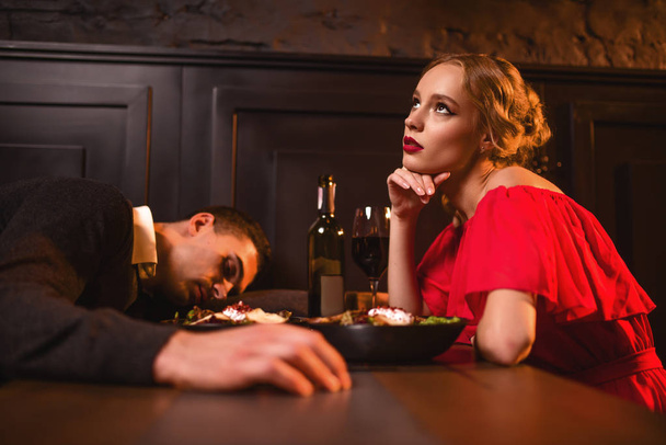 Dronken man slapen aan tafel tegen vrouw  - Foto, afbeelding