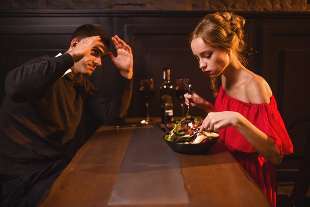 Quarrel of young couple in restaurant, bad romantic date. Elegant woman in red dress and handsome man dining  - Foto, imagen