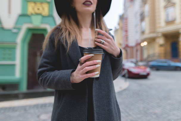 Uma mulher elegante segura uma xícara de café ou chá em suas mãos. Bebida quente nas mãos de uma mulher bonita. Mãos em close-up e em foco
. - Foto, Imagem