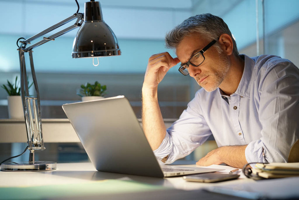 Businessman in office being thoughtful in front of laptop - Photo, image