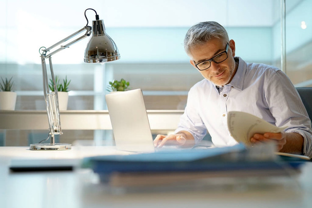 Бизнесмен, работающий в офисе с ноутбуком
 - Фото, изображение