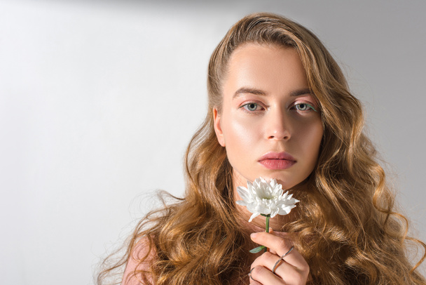 portrait of beautiful serious girl holding white flower and looking at camera  - Fotó, kép