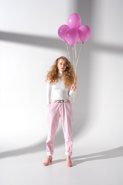 serious girl in stylish outfit standing with pink balloons with helium - Foto, imagen