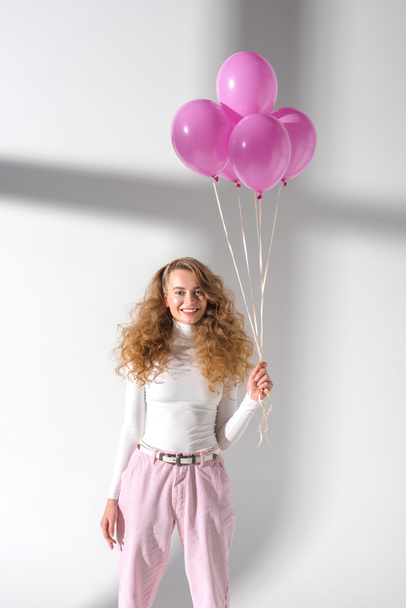 happy woman standing with balloons with helium and looking at camera - Foto, immagini