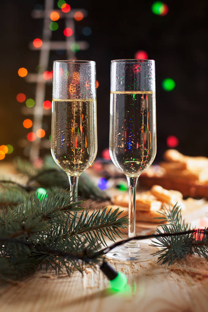 verres avec champagne, biscuits, sapin de Noël et lumières du Nouvel An sur une table de fête du Nouvel An
 - Photo, image