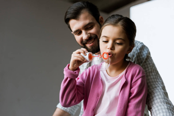 happy father with daughter blowing bubbles at home - Photo, Image