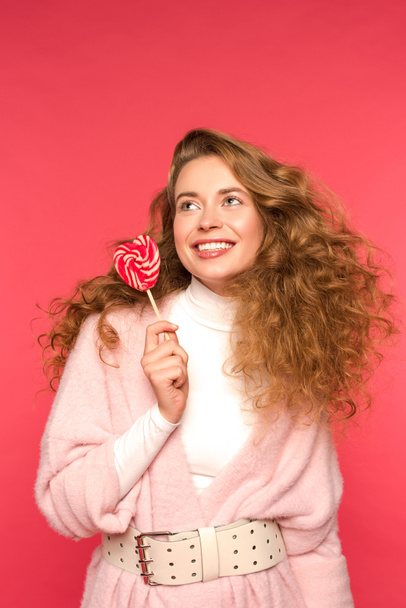 smiling girl holding heart shaped lollipop isolated on red - Photo, Image