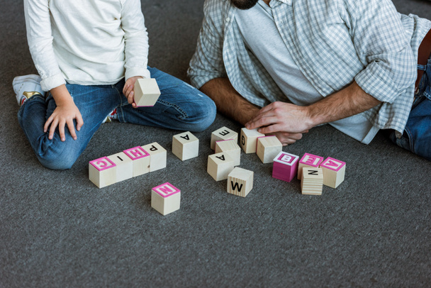 image recadrée du père avec sa fille faisant des mots par cubes avec des lettres à la maison
 - Photo, image