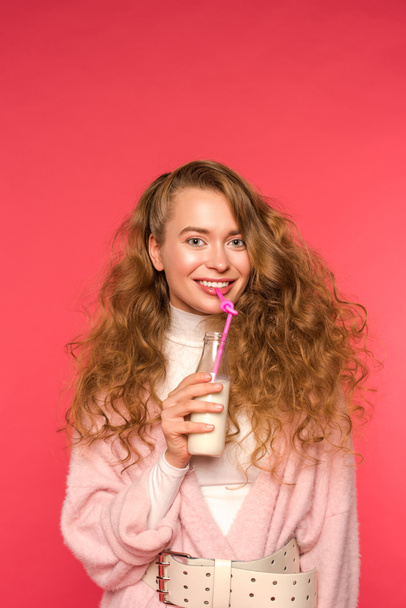 sonriente chica bebiendo milkshake aislado en rojo
 - Foto, Imagen