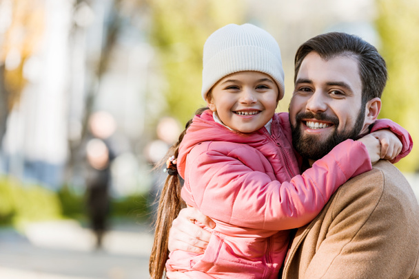 happy father with daughter hugging and looking at camera. outside - Фото, изображение