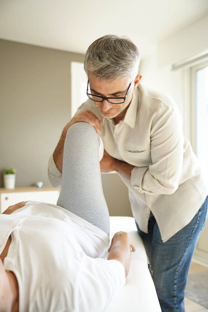 Physiotherapist stretching patient leg - Foto, imagen