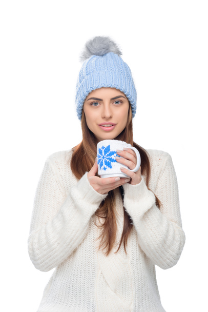όμορφη γυναίκα στο πλεκτό καπέλο και χειμώνα πουλόβερ κρατάει ζεστό φλιτζάνι καφέ, απομονώνονται σε λευκό - Φωτογραφία, εικόνα