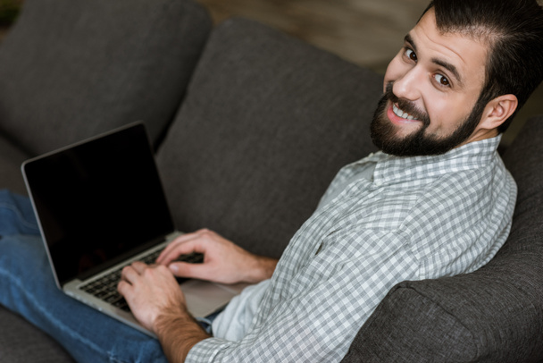 handsome man sitting on couch and using laptop - Photo, Image