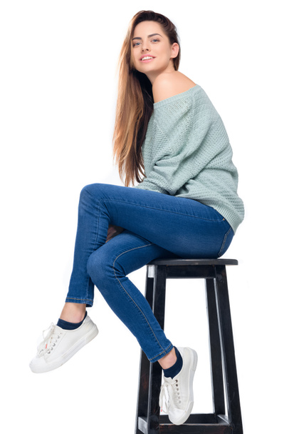 beautiful smiling girl sitting on stool, isolated on white - Foto, imagen