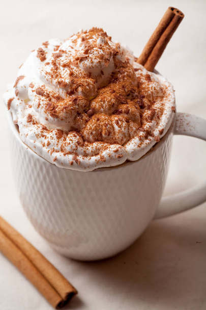 Cup of cocoa with cinnamon, whipped cream and chocolate. Textile background. Scandinavian winter concept. Vertical composition. Close up. - Fotó, kép