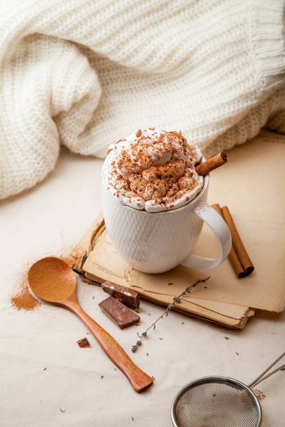 Cup of cocoa with cinnamon, whipped cream and chocolate. Textile background. Scandinavian winter concept. Vertical composition. - Foto, Imagem