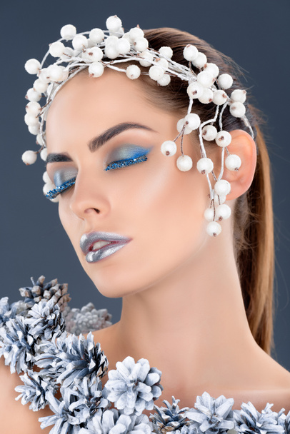 tender woman with hair accessory, christmas pine cones, winter makeup and glitter, isolated on grey - Фото, зображення