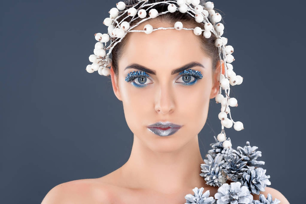 portrait of beautiful woman with hair accessory, christmas pine cones, winter makeup and glitter, isolated on grey - Фото, зображення