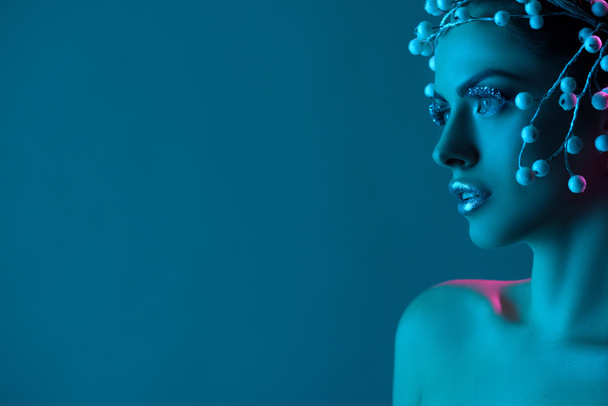 красива жінка з аксесуаром для волосся, зимовий макіяж і блиск позують для модної стрільби, ізольовані на синьому
 - Фото, зображення