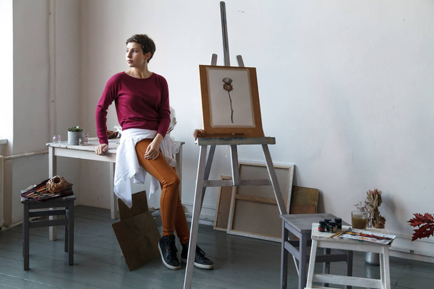 Female artist in her spacious white studio working with watercolor painting.  Natural lighting. Disclosure of creativity concept. Horizontal composition. - Foto, Imagen