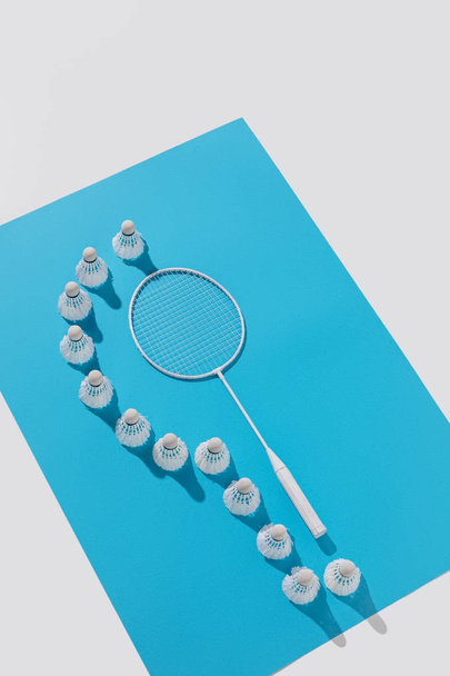 high angle view of badminton racket and shuttlecocks on blue paper, isolated on white - Photo, Image