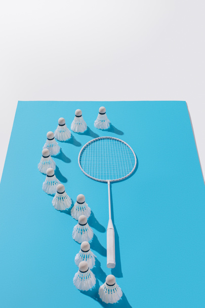 visão de alto ângulo de raquete de badminton e shuttlecocks em papel azul, isolado em branco
 - Foto, Imagem