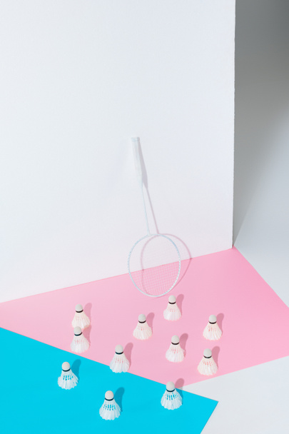 badminton racket and shuttlecocks on blue and pink papers at wall - Foto, afbeelding
