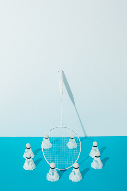 badminton racket and shuttlecocks on blue paper near white wall  - Fotografie, Obrázek