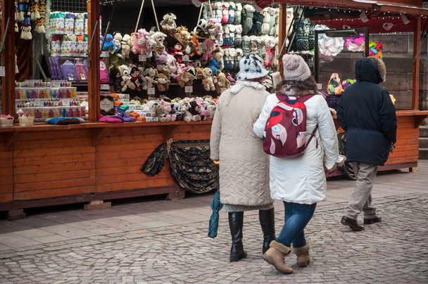 people with wool hat walking at christmas market in front of soft toys shop - Фото, зображення